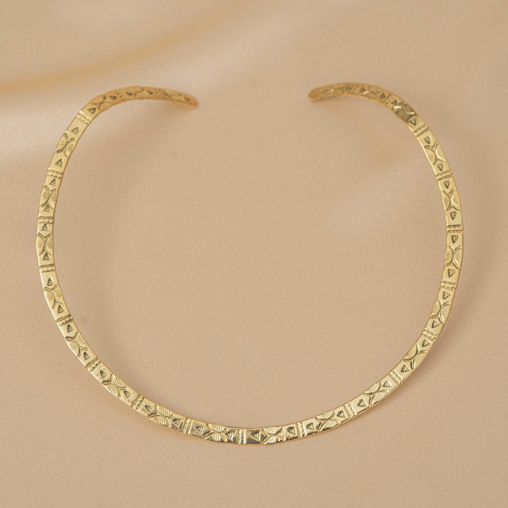 Gold necklace with geometric pattern on a beige background