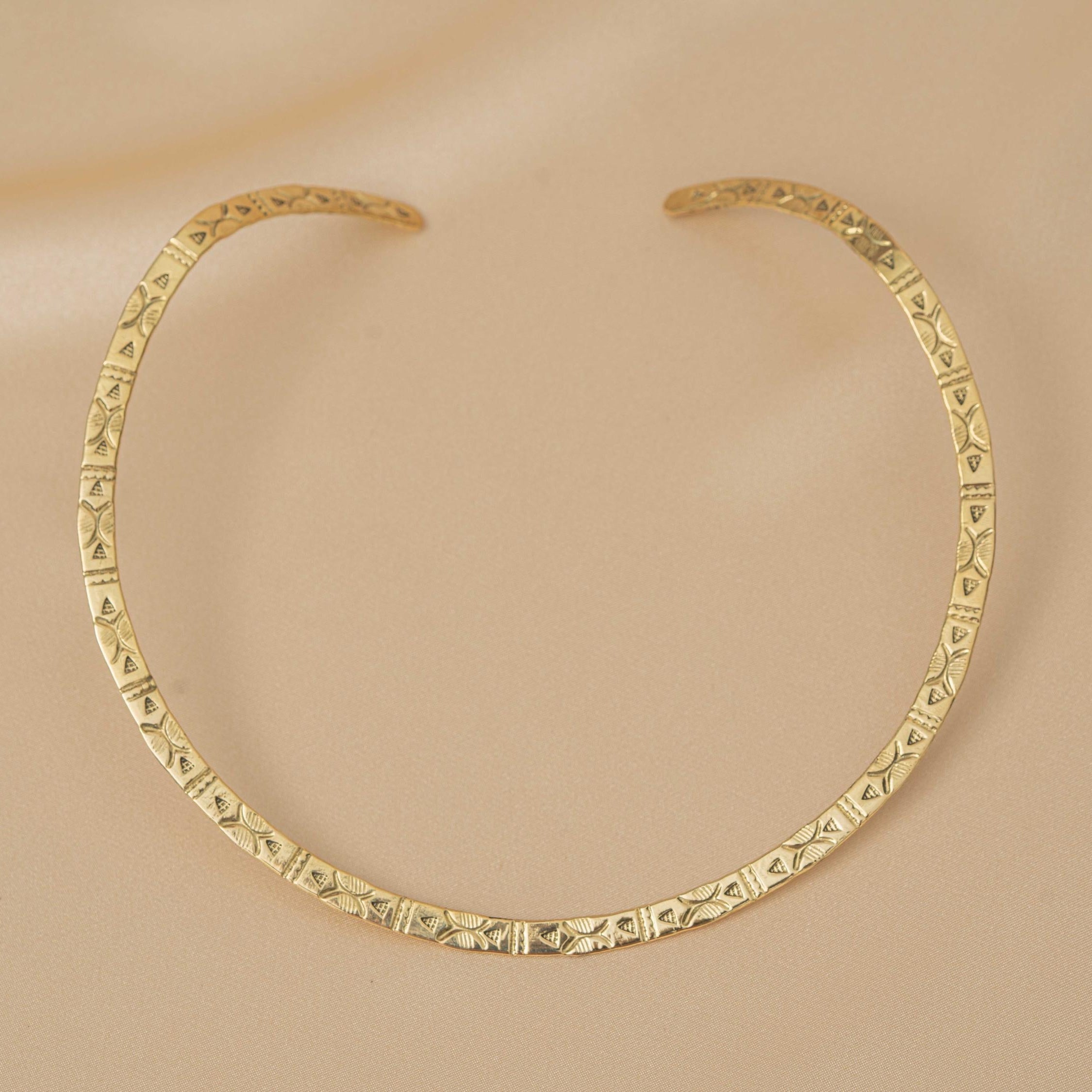Gold necklace with geometric pattern on a beige background