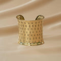 Gold bracelet cuff on a beige fabric background